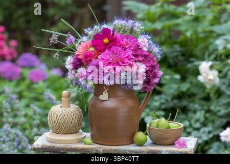 blumenarrangement mit einem Strauß aus rosa Dahlien, Hortensie-Blüten, Kosmos-Blüten, phacelia und gefiedertem Rosa in einem rustikalen Krug Stockfoto