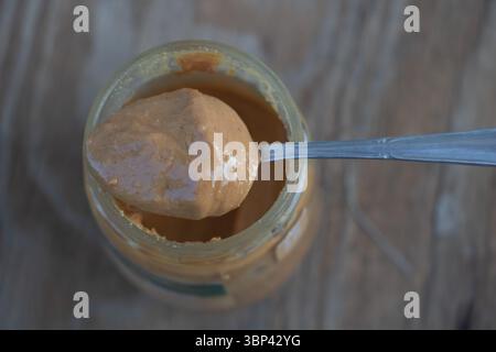 Ein Löffel Erdnussbutter aus einem offenen Glas, von oben gesehen. Stockfoto