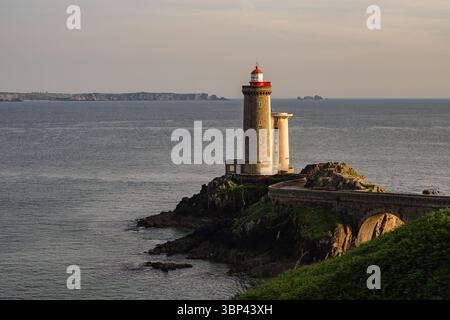Blick auf den Leuchtturm Petit Minou in der Nähe von Brest, Bretagne, Frankreich, beleuchtet von warmem Sonnenuntergang auf einer felsigen Landzunge über dem Atlantischen Ozean. Stockfoto