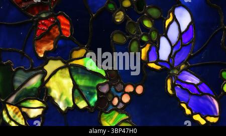 Eine Fotografie einer Buntglasscheibe mit dem Titel Butterflies and Laub von John La Farge. Tiffany Glass bezieht sich auf die vielen und vielfältigen Glasarten, die von 1878 bis 1929?1930 in den Tiffany Studios in New York City von Louis Comfort Tiffany und einem Team von anderen Designern entwickelt und hergestellt wurden, darunter Clara Driscoll, Agnes F. Northrop und Frederick Wilson. Stockfoto