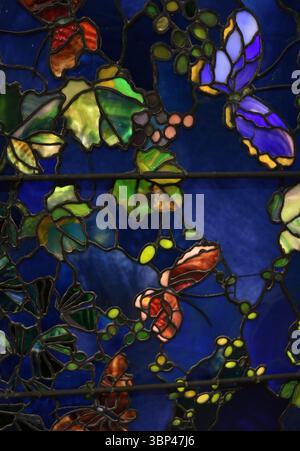 Eine Fotografie einer Buntglasscheibe mit dem Titel Butterflies and Laub von John La Farge. Tiffany Glass bezieht sich auf die vielen und vielfältigen Glasarten, die von 1878 bis 1929?1930 in den Tiffany Studios in New York City von Louis Comfort Tiffany und einem Team von anderen Designern entwickelt und hergestellt wurden, darunter Clara Driscoll, Agnes F. Northrop und Frederick Wilson. Stockfoto