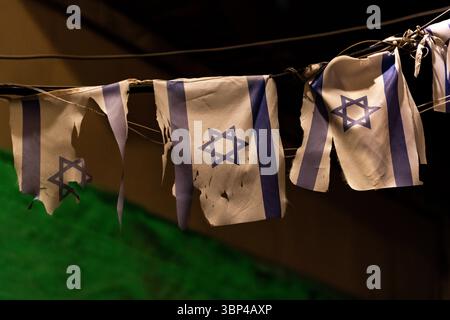 Eine Reihe kleiner, zerrissener und zerrissener israelischer Flaggen hing an einer Linie, um die Feiertage der Gedenkfeier und der Unabhängigkeitstage in Israel zu markieren. Stockfoto