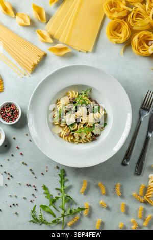 Leckere Pasta serviert mit Rucola und Käse auf einem weißen Teller Stockfoto