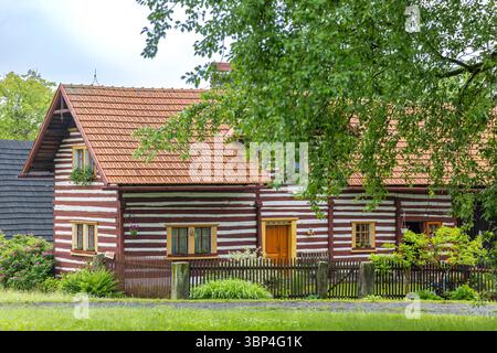 Rustikales Holzhaus mit rotem Dach in einer üppigen grünen Umgebung Stockfoto
