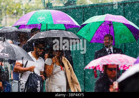 London, Großbritannien. Juli 2025. Tennis: Grand Slam/WTA Tour/ATP Tour - Wimbledon. Die Zuschauer laufen mit Sonnenschirmen auf dem Platz. Frank Molter/dpa/Alamy Live News Stockfoto