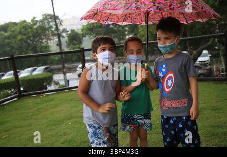 Kind mit Maske während covid-19 salvador, bahia, brasilien - 15. Mai 2021: Kinder unter einem Regenschirm in einem Park in der Stadt Salvador geschützt. SALVADOR BAHIA BRASILIEN Copyright: XJoaxSouzax 150521JOA558 Stockfoto
