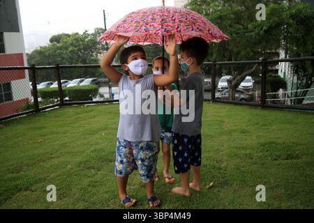 Kind mit Maske während covid-19 salvador, bahia, brasilien - 15. Mai 2021: Kinder unter einem Regenschirm in einem Park in der Stadt Salvador geschützt. SALVADOR BAHIA BRASILIEN Copyright: XJoaxSouzax 150521JOA557 Stockfoto
