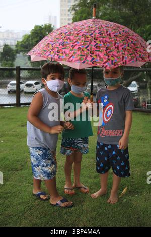 Kind mit Maske während covid-19 salvador, bahia, brasilien - 15. Mai 2021: Kinder unter einem Regenschirm in einem Park in der Stadt Salvador geschützt. SALVADOR BAHIA BRASILIEN Copyright: XJoaxSouzax 150521JOA559 Stockfoto