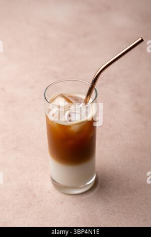 Kaffee mit Kokosmilch und Eiswürfeln in einem hohen Glas. Traditionelles alkoholfreies kaltes Getränk. Im Hintergrund ein Glas Kaffee und ein Glas Zucker. S Stockfoto