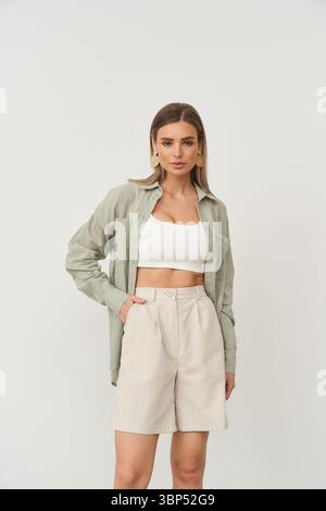 Stilvolles weibliches Model, das drinnen in modischem Outfit mit natürlichem Make-up posiert Stockfoto