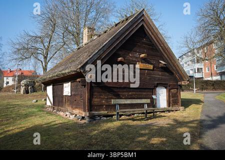 Ein charmantes historisches Holzhaus mit Strohdach und Holzbank steht an einem sonnigen Tag in Hässleholm, Schweden. Stockfoto