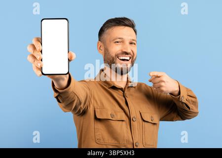 Glücklicher Junger Mann, Der Auf Ein Leeres Smartphone In Der Hand Zeigt Stockfoto