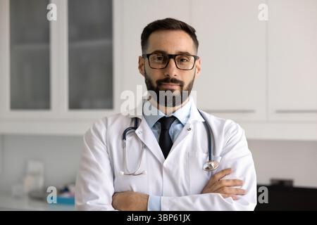 Positiver gutaussehender hispanischer Arzt, der im Krankenhausbüro steht Stockfoto