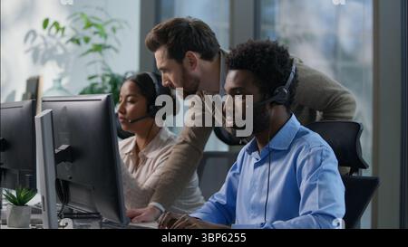 Callcenter Teamwork multikulturelle Büromitarbeiter unterstützen Kommunikation afrikanischer Mann indische Frau Headset Computer Helpdesk Kaukasischer Vorgesetzter Stockfoto