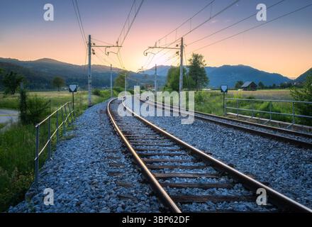 Eisenbahngleise verschwinden in den Sonnenuntergang auf dem Land Stockfoto