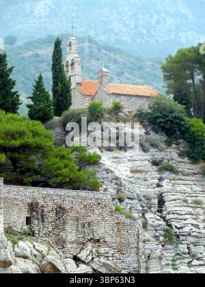 Besucher bewundern die malerische Landschaft des Ferienorts Sveti Stefan Island in Montenegro mit bezaubernden Steinhäusern inmitten von üppigem Grün Stockfoto