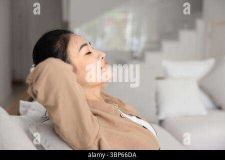 Seitenansicht einer ruhigen vietnamesischen Frau, die sich auf der Couch entspannte Stockfoto