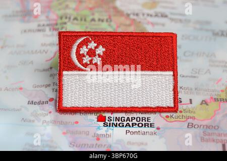 Singapur Nationalflagge und SG Flagge auf Textil gestickt über Singapur Asien Karte. Zeichen für kulturelle Reisen und Nationalstolz. Stockfoto