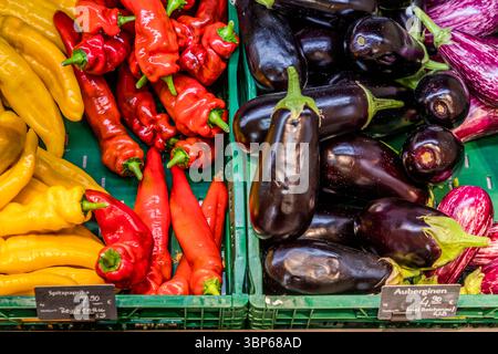 Spitze Paprika und Auberginen liegen frisch geerntet in Kisten zum Verkauf auf der Gemüseinsel Reichenau, preislich bei 7,90 Euro pro Kilo für die Paprika und 4,30 Euro pro Kilo für die Auberginen. Im Jahr 2024 bewirtschafteten 39 Produzenten auf der Insel 70 verschiedene Gemüsesorten, darunter mehr als 3.000 Tonnen Paprika. Marktstraße, Reichenau, Baden-Württemberg, Deutschland. Stockfoto