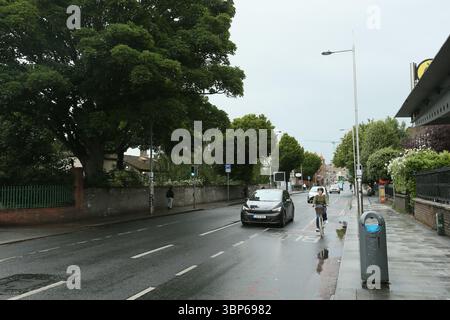 Dublin, Irland - 06. Juni 2025 - Lmage der Rathmines Road Lower, wenn Autos an einer Bushaltestelle vorbeifahren, an einem nassen Nachmittag Stockfoto
