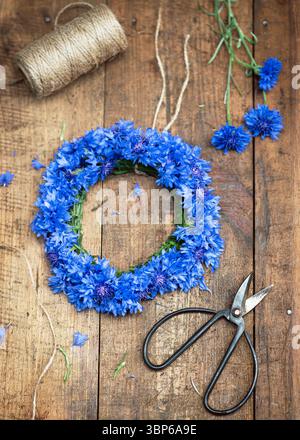 Blick von oben auf den Blumenkranz aus wunderschönen, frischen, tiefblauen Kornblumen (Centaurea cyanus). Handgefertigtes floristisches Konzept. Selektiver Fokus. Stockfoto