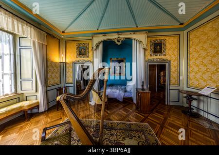 Zimmer im Napoleon Museum mit Himmelbett, Harfe und anderen Möbeln. Gelbe Tapete bedeckt die Wände. Die Decke ist blau gestreift. Salenstein, Arenenberg, Thurgau, Schweiz, Europa Stockfoto