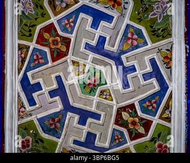 Ein lebendiges, kompliziertes geometrisches Muster mit Blumenmustern in verschiedenen Farben, darunter Blau, Grün, Rot und weiß. Die Grafik zeigt eine Mischung Stockfoto