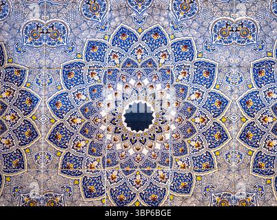 Ein lebendiges und kompliziertes Mosaik mit geometrischen Mustern in Blau, Gelb und weiß. Die Konstruktion wird von einem zentralen Punkt aus abgestrahlt und erzeugt ein mesm Stockfoto