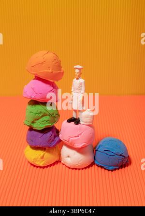 Mehrfarbige Eislöffel und Küchenspielzeug auf gelbem und orangefarbenem Hintergrund. Lebendige Farben Stockfoto