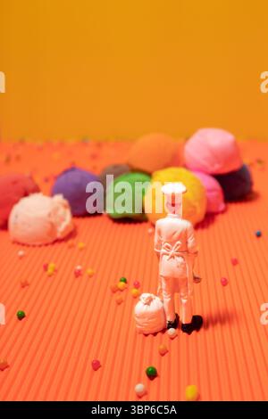 Küchenspielzeug und mehrfarbige Eislöffel auf orangefarbenem und gelbem Hintergrund. Lebendige Farben Stockfoto