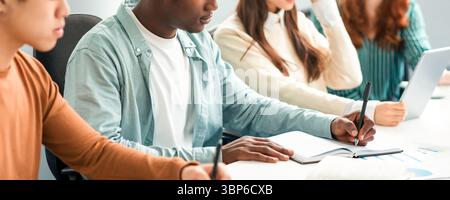 Verschiedene Studenten Sitzen Am Schreibtisch In Der Reihe Und Nehmen Notizen Stockfoto