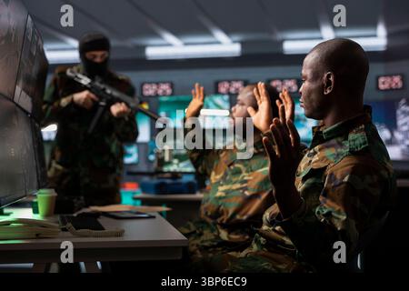 Gefährlicher Terrorist bedroht Soldaten mit Gewehren im Kommandoposten. Ein Aufständischer benutzt Waffen, um afroamerikanische Geiseln bei der Entführung der feindlichen Basis zu kontrollieren, während eines bewaffneten Konflikts im Guerillakrieg Stockfoto