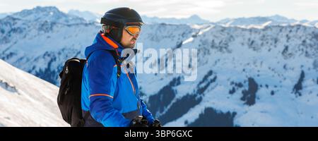 Junger Erwachsener, selbstbewusstes Skier-Porträt im alpinen Winterskigebiet. Männliche sportliche Person mit Rucksack Berg Alpen Schneehang draußen kalt Schnee Tag Stockfoto