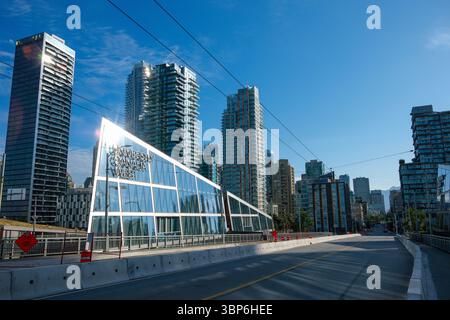 Das Sonnenlicht tanzt am Punkt des Gebäudes der University Canada West entlang der Granville Street Bridge mit der Innenstadt von Vancouver in der Ferne. Stockfoto
