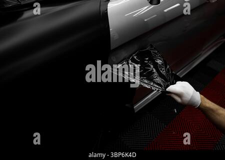 Die Anwendung „Auto Wrap“ ändert das Erscheinungsbild des Fahrzeugs. Vinyl-Verpackung Für Autos Mit Vollpaneel. Die großformatige Vinylfolie verwandelt das Außendesign des Fahrzeugs Stockfoto