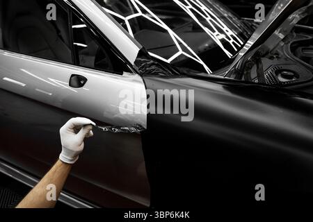 Die Anwendung „Auto Wrap“ ändert das Erscheinungsbild des Fahrzeugs. Vinyl-Verpackung Für Autos Mit Vollpaneel. Die großformatige Vinylfolie verwandelt das Außendesign des Fahrzeugs Stockfoto