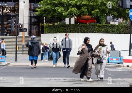 London, Großbritannien, 9. Mai 2025 Afrikanische Frau, Kaukasierin, junger Mann, zwei junge Erwachsene Frauen aus dem Nahen Osten überqueren eine geschäftige City Street Stockfoto