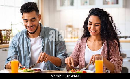 Das tägliche Leben des Paares. Glückliche Ehegatten aus dem Nahen Osten, die in der Küche frühstücken Stockfoto