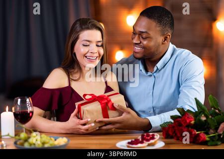 Valentinstag-Feier. Happy Romantic Interracial Paar Essen Im Restaurant, Austausch Von Geschenken Stockfoto