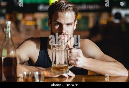 Mann, der allein im Pub sitzt. Mann mit Alkohol. Trauriger Kerl in der Bar. Der Typ in der dunklen Bar. Alkoholproblem. Einsamer Mann trinkt Whiskey im Restaurant. Depressiver Mann Stockfoto