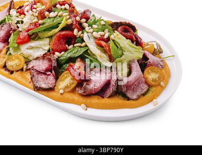 Speisen, Ein lebendiger Salat mit zartem gegrilltem Fleisch, frischem Gemüse, gebratenen Paprika, Kirschtomaten und Pinienkernen. Dieses Gericht ist wunderschön zubereitet Stockfoto