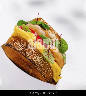 Essen, leckeres Sandwich mit Garnelen, Rührei, Salat und Sauce in einem weißen Karton auf weißem Hintergrund Stockfoto
