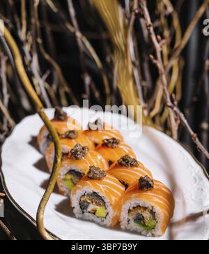 Essen, exquisite Lachs-Sushi-Brötchen mit Trüffeln, präsentiert auf einem stilvollen weißen Teller mit künstlerischem Hintergrund Stockfoto