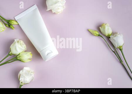 Mock up Hautpflege Kosmetik-Paket auf rosa. Kosmetisches Produkt. Weißes kosmetisches Produkt in Röhren auf farbigem Hintergrund mit blühenden Eustoma-Blüten. Cosmet Stockfoto