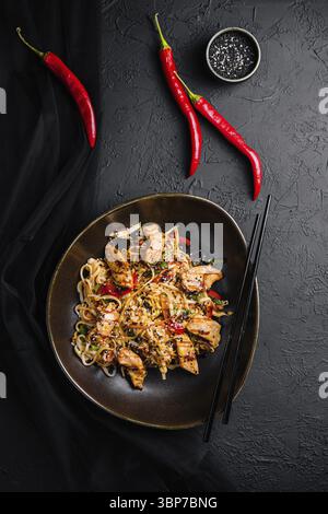 Nudeln mit Gemüse und Huhn in einer schwarzen Schüssel anbraten Stockfoto