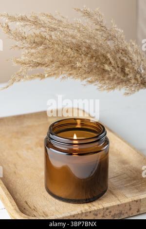 Bio Duftkerze aus Soja in dunklem Glas auf dem Bambustablett. Minimalismus Konzept. Nahaufnahme, Kopierraum für Text Zero Waste Minimalismus Konzept, Hand Stockfoto