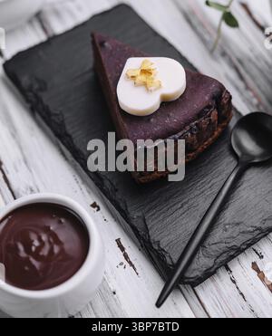 Essen, Sacher-Tortenscheibe und Schokoladencreme auf Holz Stockfoto