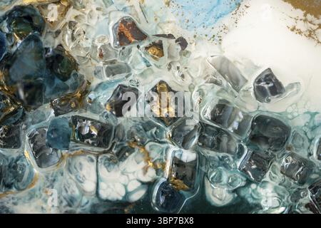 Nahaufnahme von Epoxidharz mit natürlichen Mineralien, Kristallen und Steinen, Malen von Geoden, die lebendige Pigmente und Farben mischen. Die Textur der Epoxidharzwirkung Stockfoto