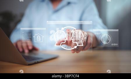 Person, die mit holografischen menschlichen Köpfen, Smart Home und globalen Netzwerksymbolen interagiert und digitales Lernen, Wissenstransfer und Smart te repräsentiert Stockfoto