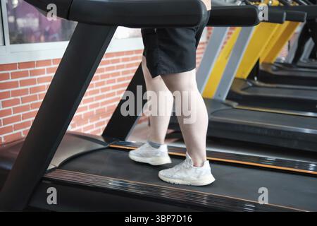 Eine Person läuft auf einem Laufband in einem Fitnessstudio. Die Person trägt Shorts und weiße Turnschuhe Stockfoto